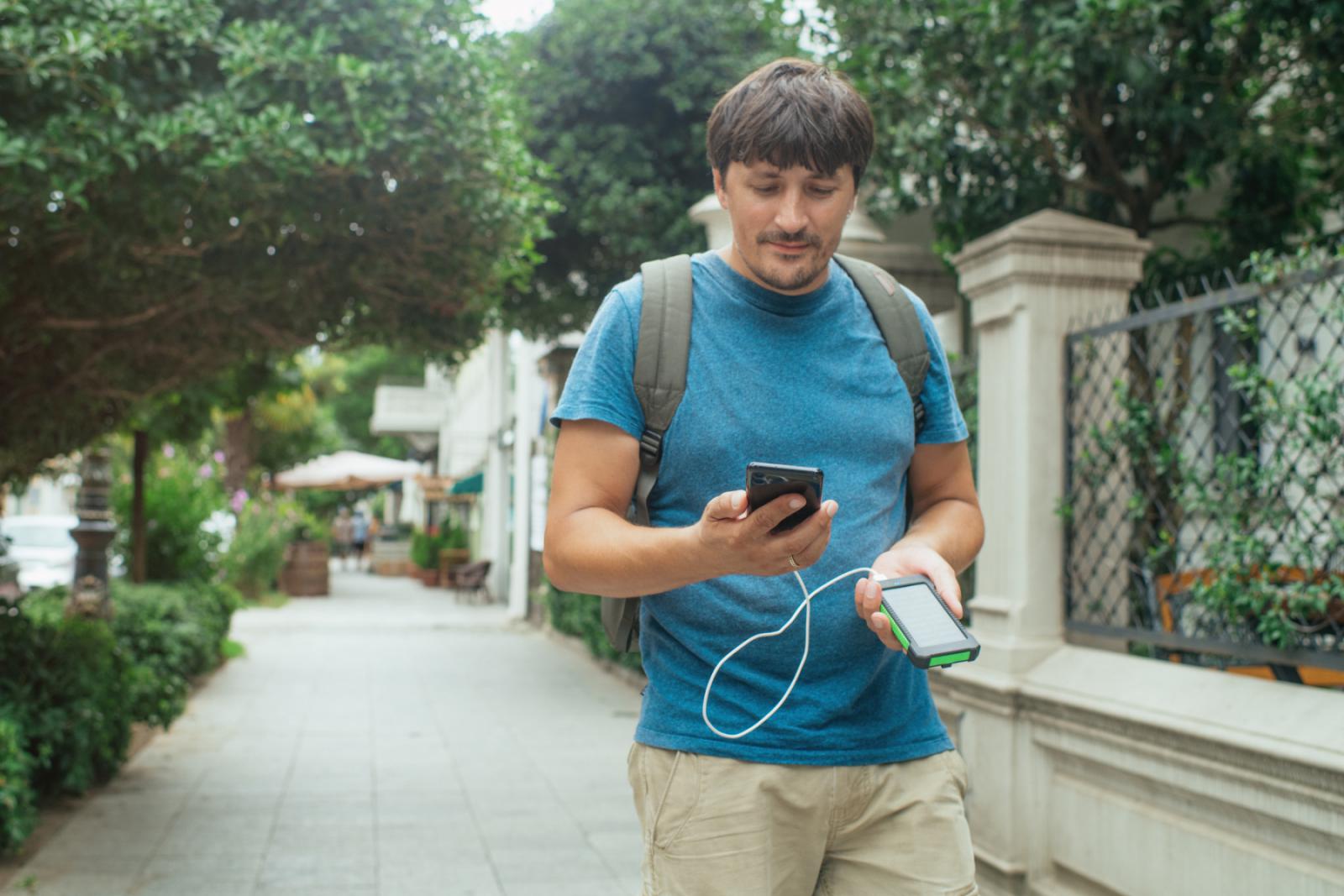 man gebruikt powerbank tijdens stadswandeling