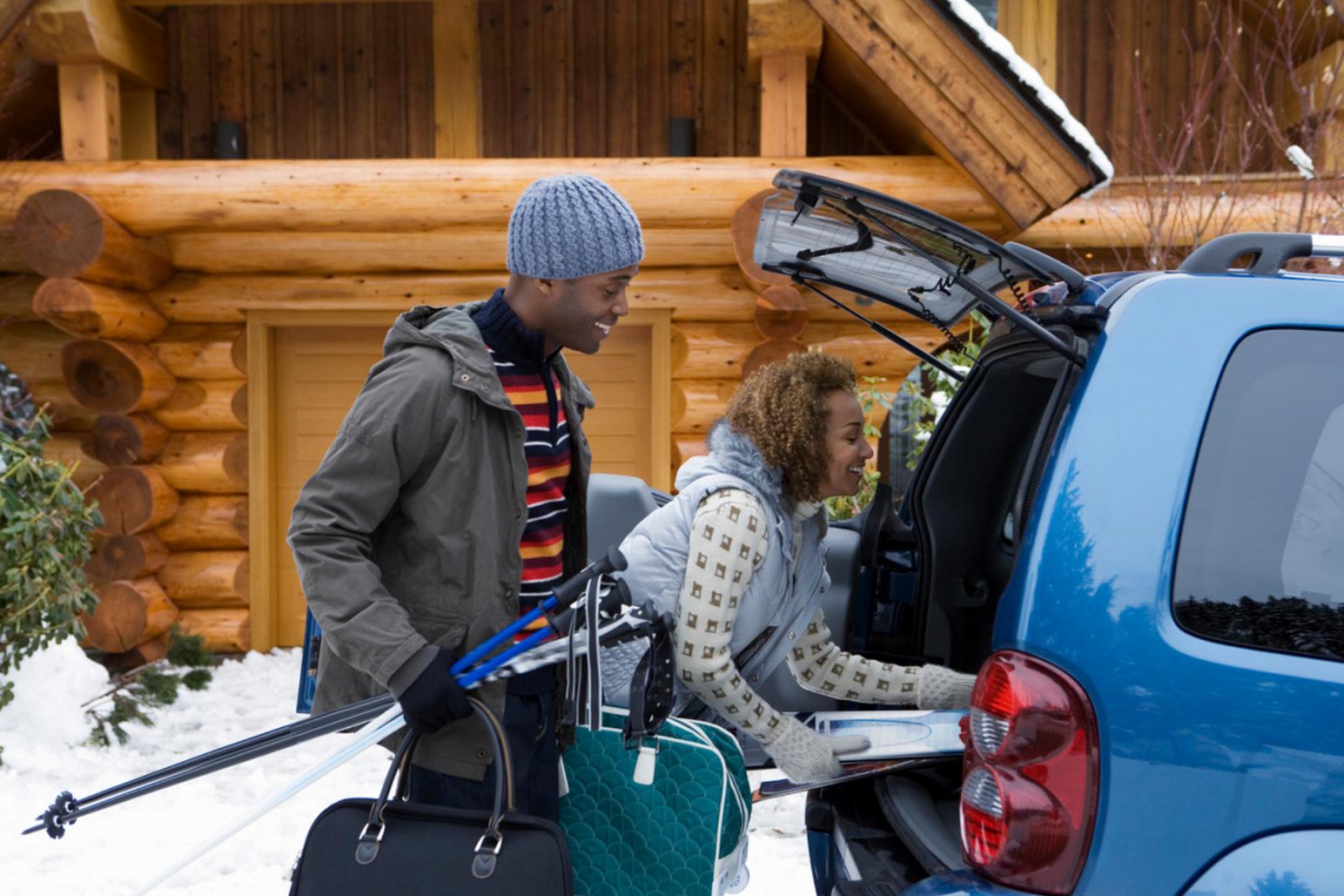 Twee mensen laden de auto in met skispullen voor een wintersportvakantie